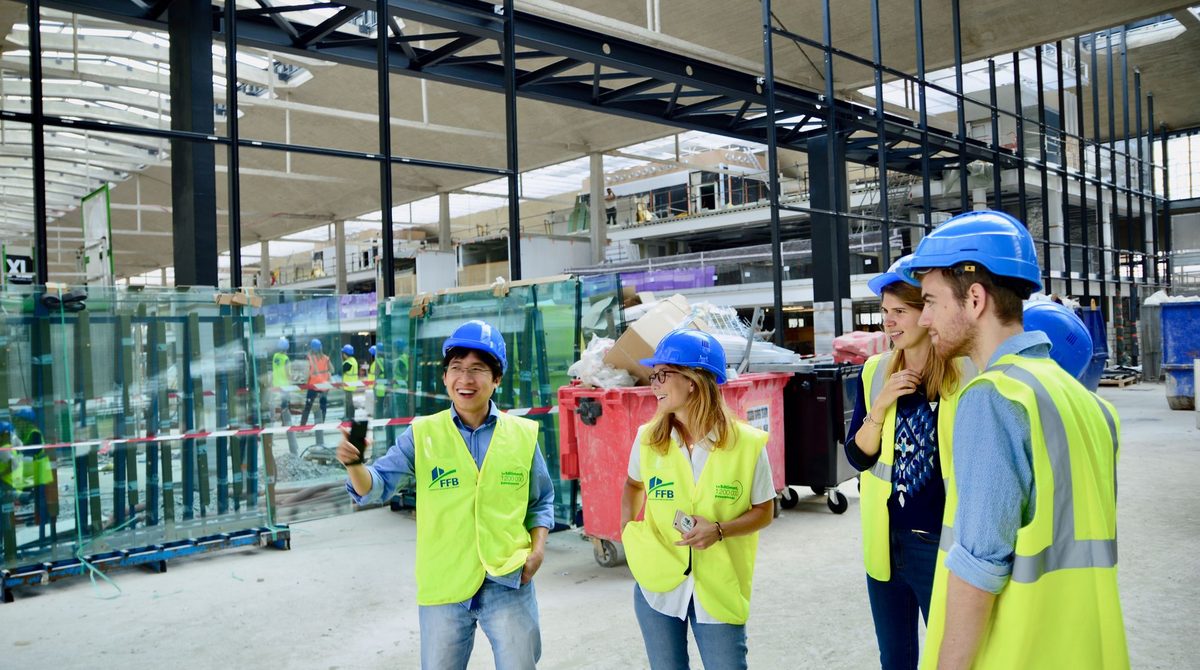 Réunion de chantier : équipe en gilets haute visibilité et casques échangeant sur le projet, dans un bâtiment en construction