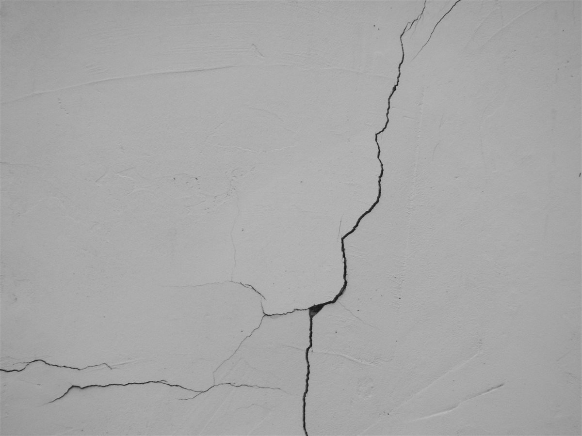 Fissure marquée traversant un mur clair, illustrant une pathologie du bâtiment à diagnostiquer
