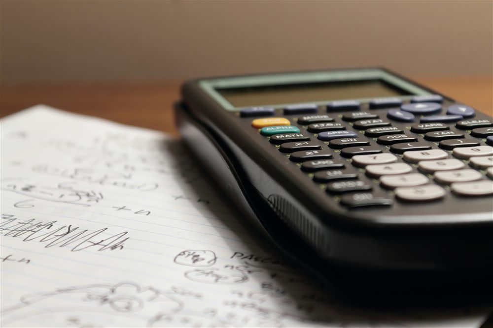 Calculatrice posée sur des feuilles de calcul, illustrant la vérification chiffrée d'une note de calcul