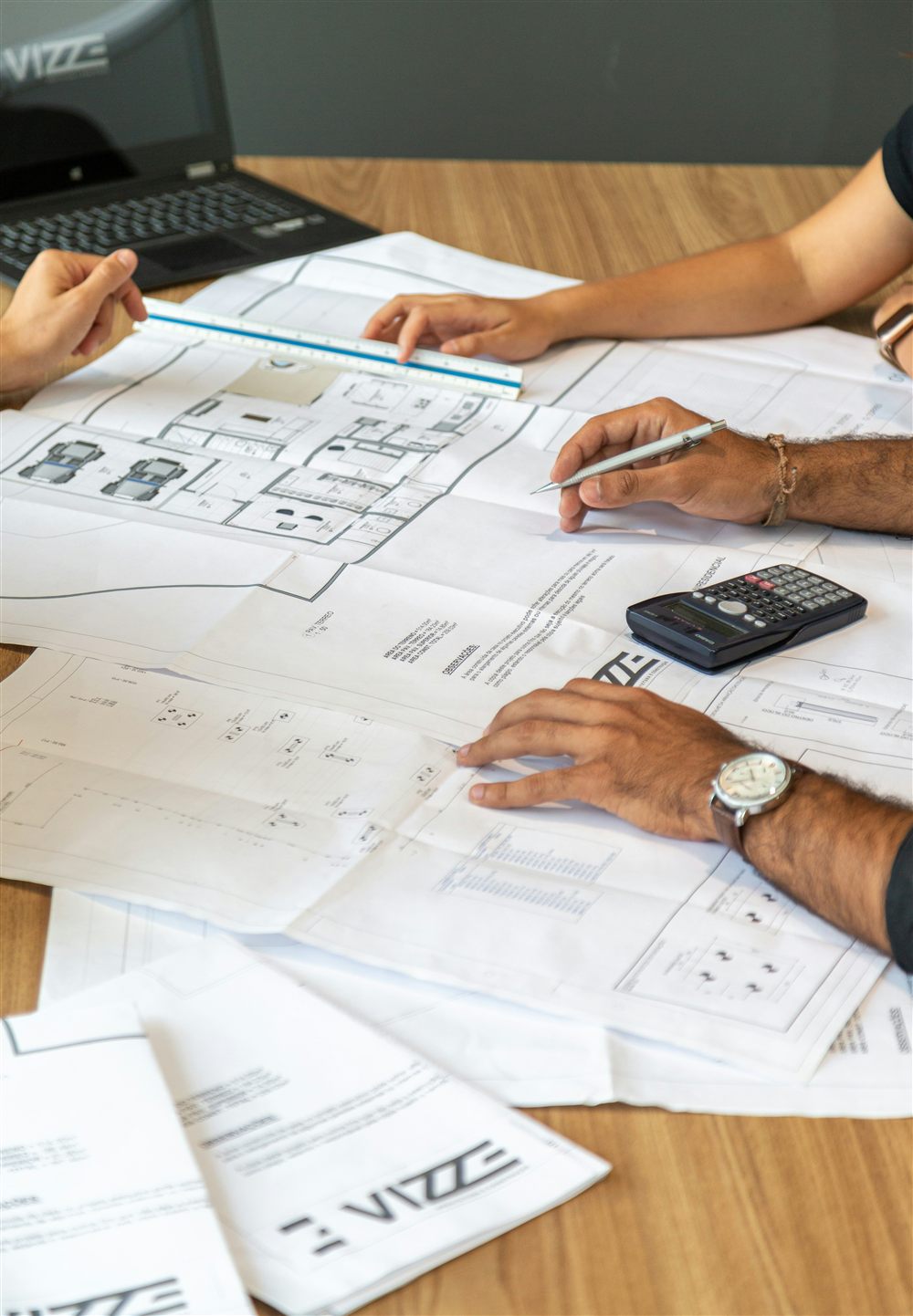 Professionnels réunis autour de plans de structure étalés sur un bureau pour en examiner les résultats