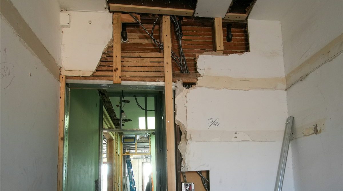 Ouverture pratiquée dans un mur intérieur en cours de rénovation, structure mise à nu au-dessus de la baie