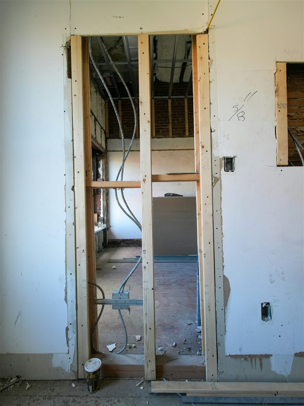 Baie ouverte dans un mur en cours de chantier, encadrement et réseaux électriques apparents