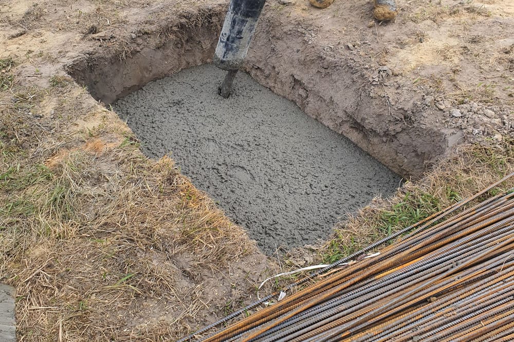 Béton coulé dans une fouille de fondation, avec les aciers HA en attente au premier plan