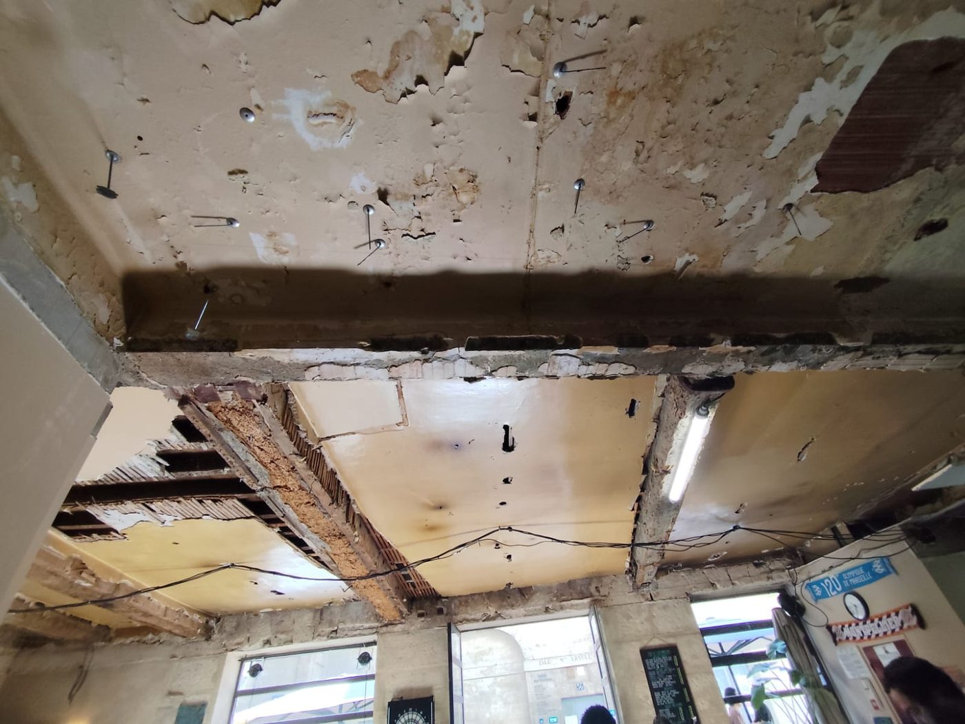 Vue d'ensemble du plafond : poutre maîtresse en bois et solives apparentes après dépose partielle des plâtres