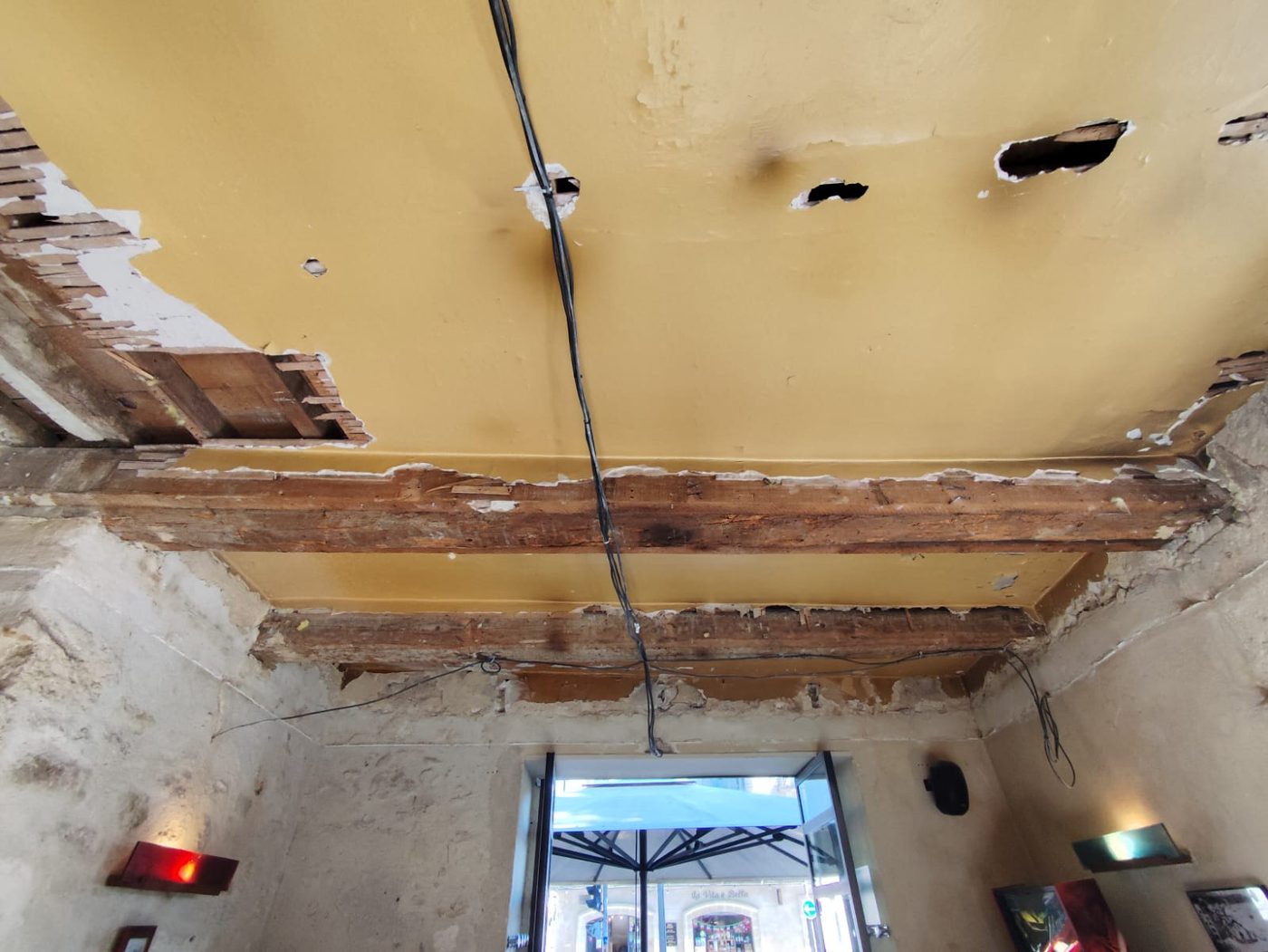 Poutre bois traversante et gaine électrique en plafond, au-dessus de la vitrine