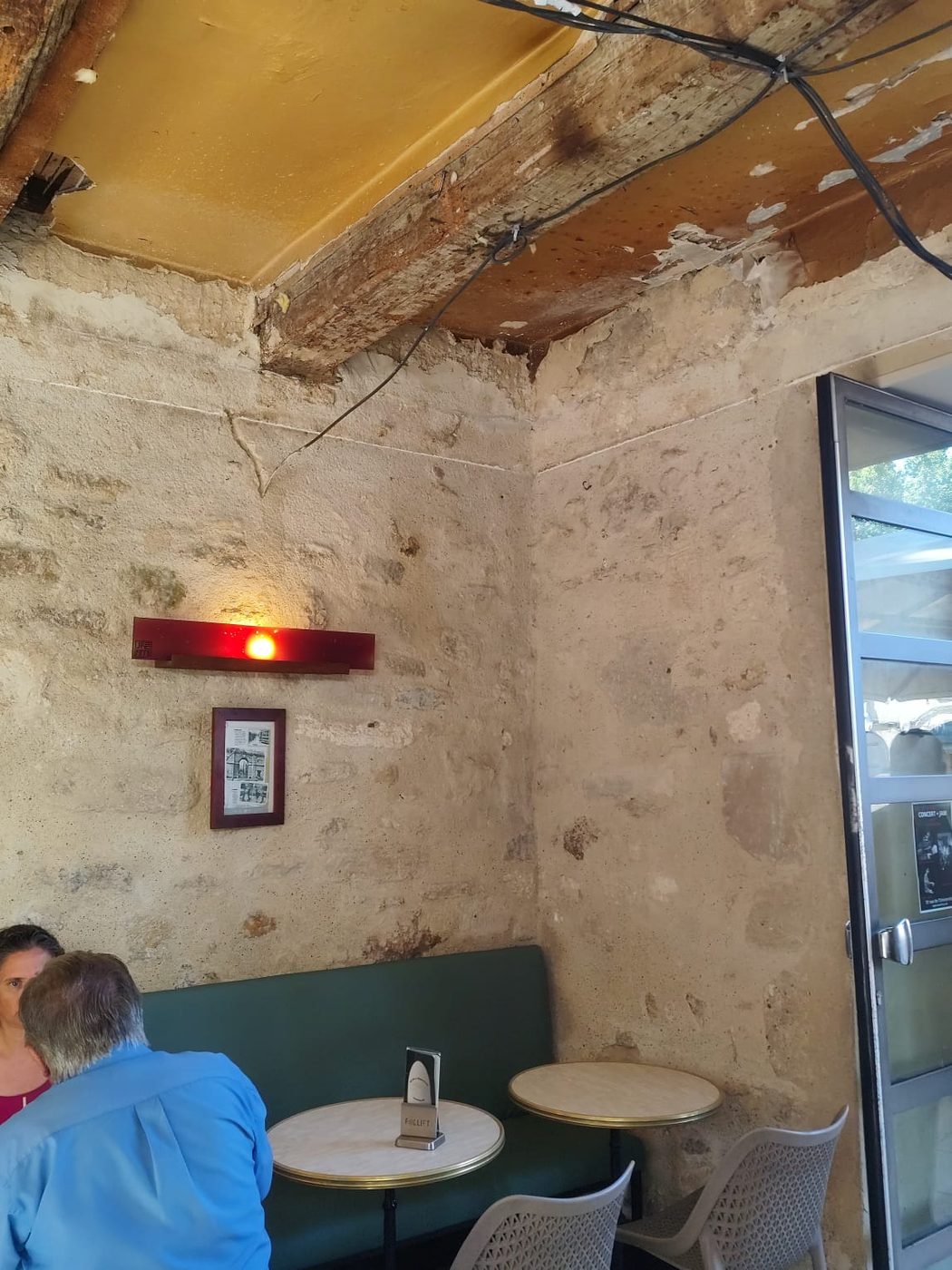 Salle du bar avec mur en pierre apparente et poutre bois en plafond