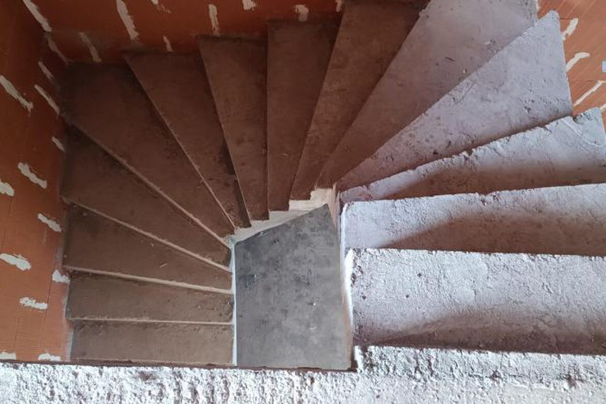 Escalier en béton armé coulé en place, marches balancées vues de dessus, murs en briques apparentes